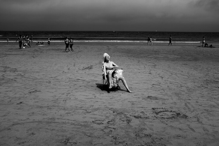 Ασπρόμαυρη φωτογραφία γυναίκας καθισμένης σε καρέκλα σε παραλία