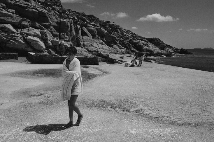 Ασπρόμαυρη φωτογραφία αγοριού σε παραλία τυλιγμένο με πετσέτα