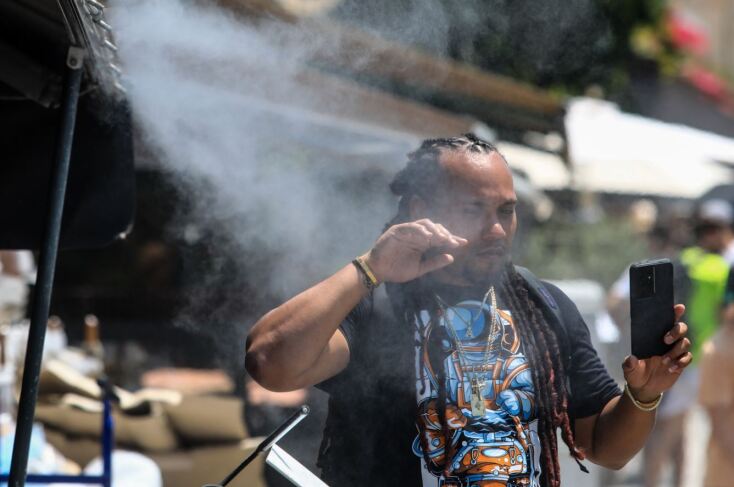 Πολίτης περνά μπροστά από ανεμιστήρα που ψεκάζει νερό