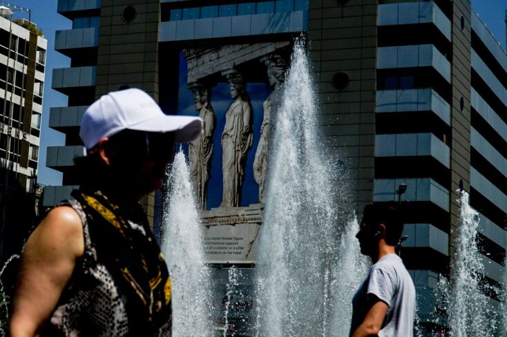 Γυναίκα περνά μπροστά από το συντριβάνι στο Σύνταγμα