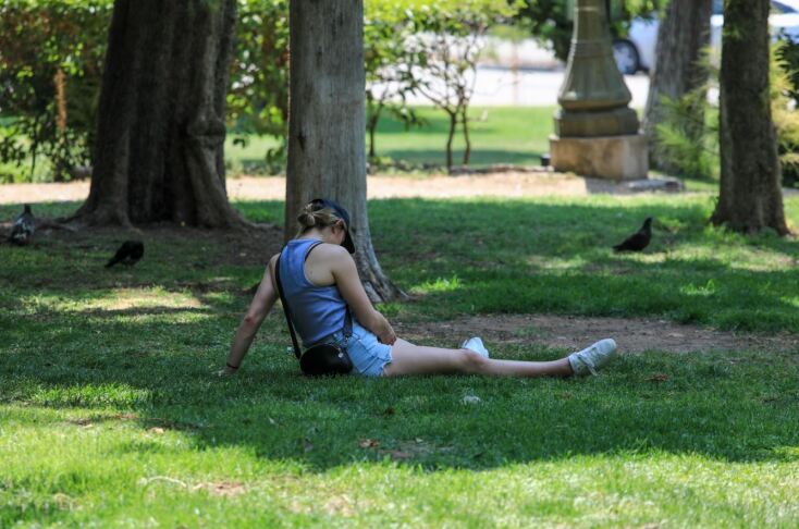 Τουρίστρια έχει ξαπλώσει στο γρασίδι, εξασφαλίζοντας λίγη σκιά