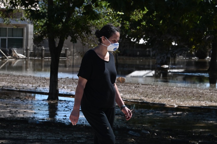 Γυναίκα με μάσκα περπατά σε δρόμο με λάσπη στη Θεσσαλία