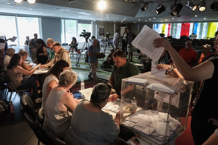 Εκλογικό κέντρο του ΣΥΡΙΖΑ και πολίτες που ακούν τα εκλογικά τους καθήκοντα