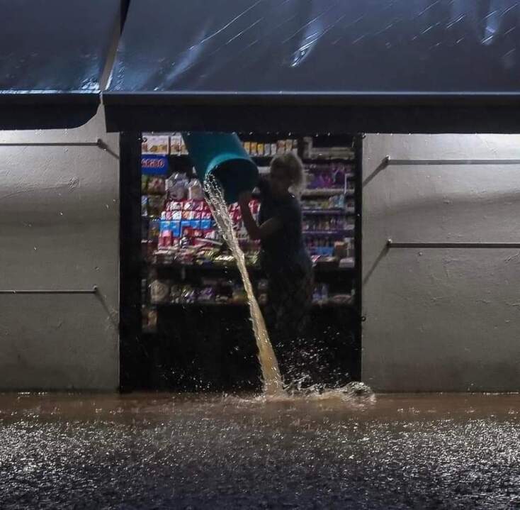 Γυναίκα με κουβά διώχνει τα νερά από το κατάστημά της στην Αγριά του Βόλου