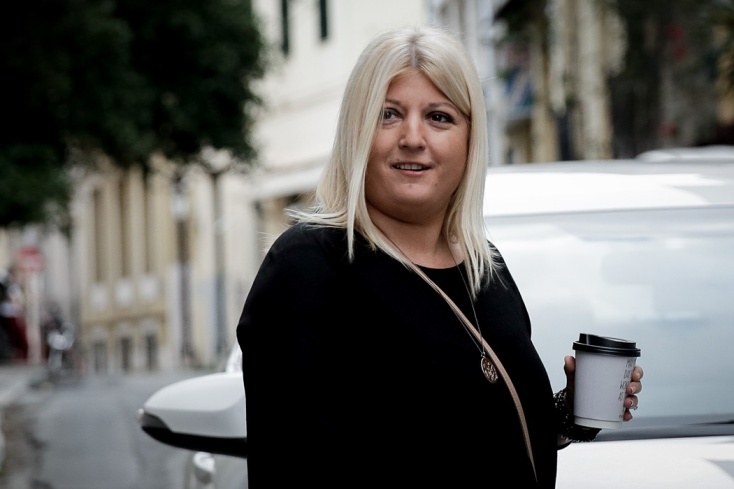 Η Γεωργία Γεννιά με καφέ στο χέρι ποζάρει χαμογελαστή στον φωτογραφικό φακό