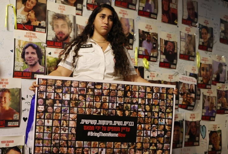 Γυναίκα κρατά πανό με τις φωτογραφίες ομήρων της Χαμάς