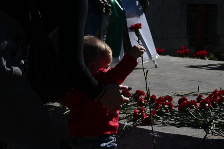 Παιδάκι με τη βοήθεια της μητέρας του αφήνει ένα κόκκινο γαρύφαλλο στο Πολυτεχνείο