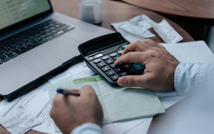 Άτομο κάνει υπολογισμούς και σημειώνει σε χαρτί