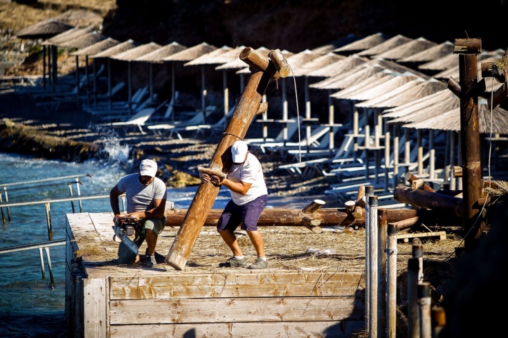 Εργάτες απομακρύνουν κορμούς από παραλία όπου έχει γίνει παραβίαση των χρήσεων γης