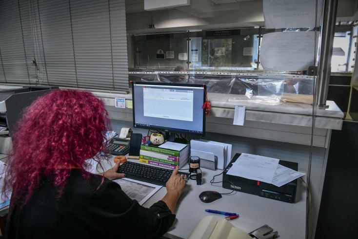 Γυναίκα με κόκκινα μαλλιά πλάτη στον φακό σε υπηρεσία συντάσσει φορολογική δήλωση στον υπολογιστή της