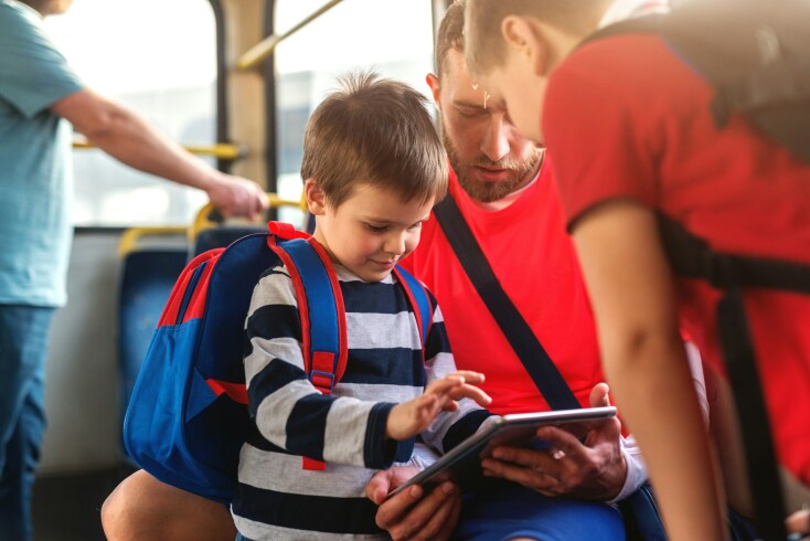 Παιδί με τη σχολική του τσάντα κοιτάει σε τάμπλετ