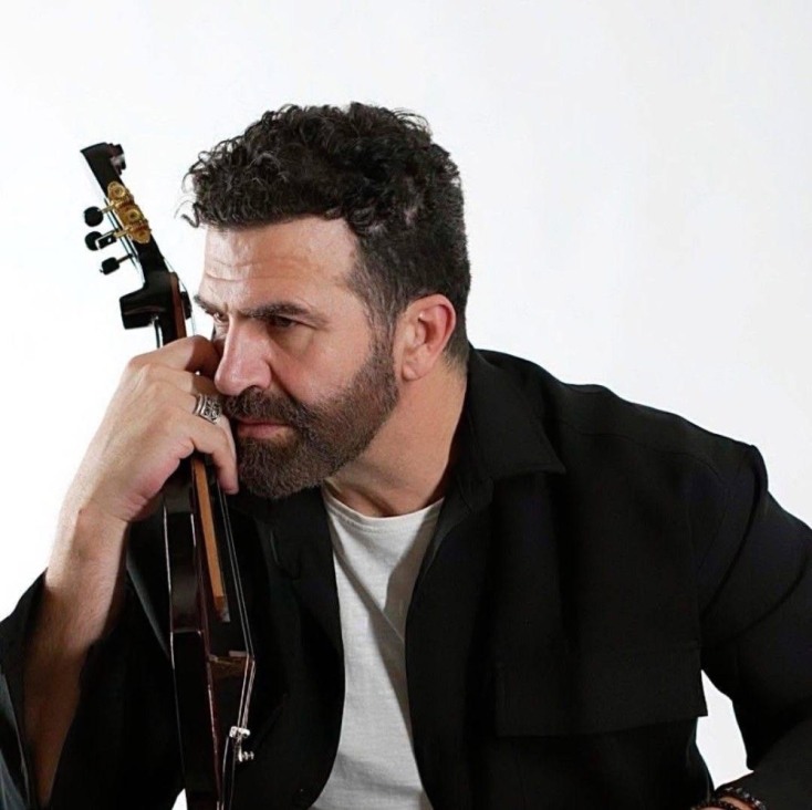 O Ηλίας Παλιουδάκης κρατώντας παραδοσιακό μουισκό όργανο