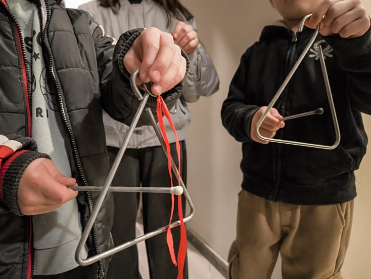 Παιδιά με τρίγωνα στα χέρια λένε τα κάλαντα