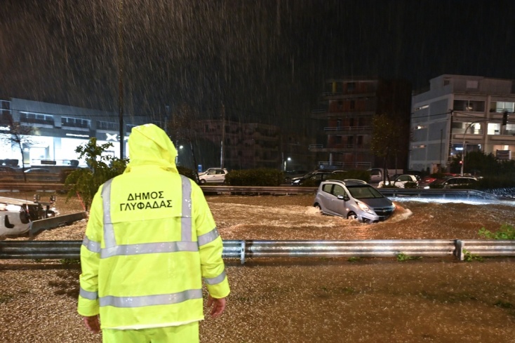 Υπάλληλος του δήμου Γλυφάδα σε σημείο δρόμου που έχει μετατραπεί σε ποτάμι