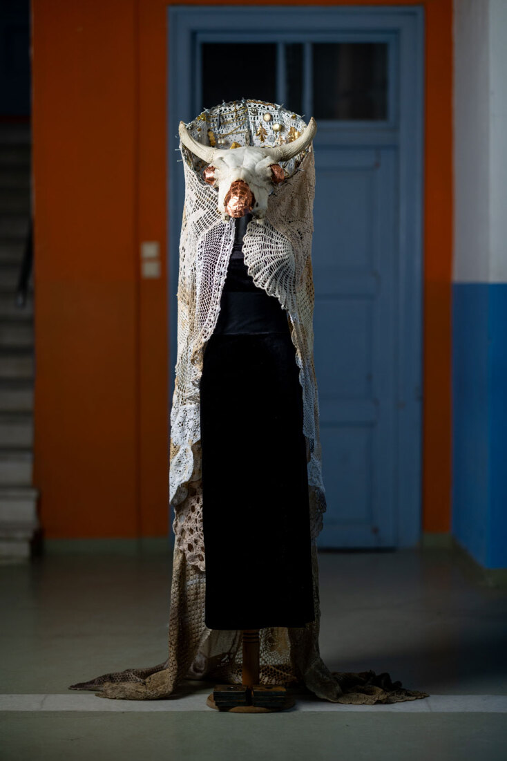 Μαρία Φωκά | VOOS σάιμποργκ, 2026 | 190x95x140 εκ. Κάπα από κληρονομηθέντα σεμέν της δεκαετίας του '70, τσέρκι, objetstrouvés, κειμήλια και ευτελή παραφερνάλια / κρανίο βοός, φύλλα χαλκού και χάλκινο σύρμα / φόρεμα από μαύρο βελούδο δεύτερο χέρι