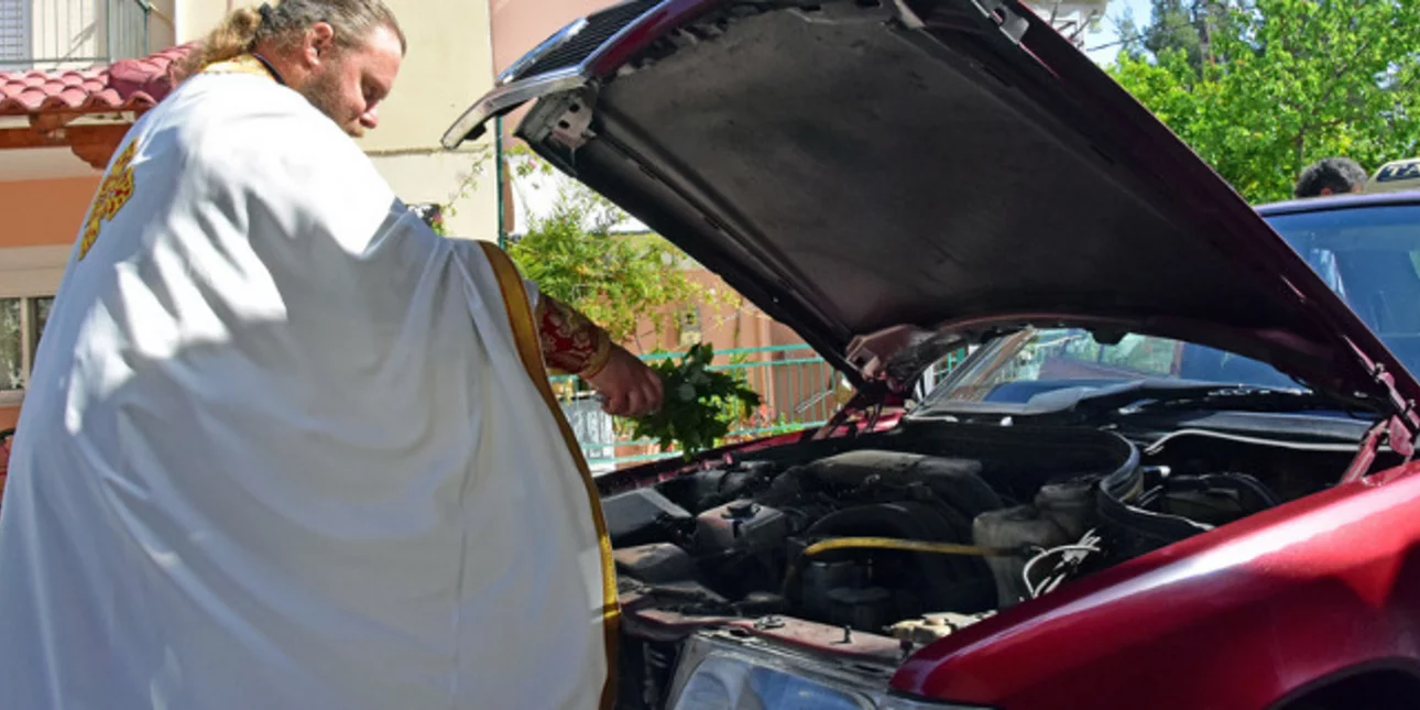 Ιερέας κάνει αγιασμό σε καπό αυτοκινήτου