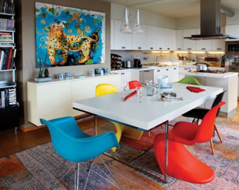 Μια τραπεζαρία με τη χαρά της ζωής. Χρώμα πολύ από τον πίνακα και τις καρέκλες της Vitra, ένα τραπέζι που χωράει όλη την παρέα και, για οικονομία κινήσεων, η κουζίνα σε απόσταση αναπνοής. image