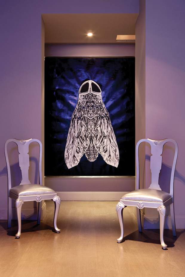 Η κουζίνα είναι κρυμμένη πίσω από μετακινούμενα πάνελ, που ταυτόχρονα «καδράρουν»τη Μύγα της Ραλλούς Παναγιώτου. Καρέκλες φαγητού, κι αυτές του Σαρίδη