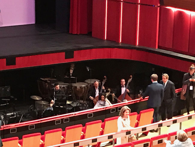 Η ζωντανή ορχήστρα η οποία βρίσκεται στο χώρο μεταξύ σκηνής και πλατείας «ζεσταίνει» τα όργανα