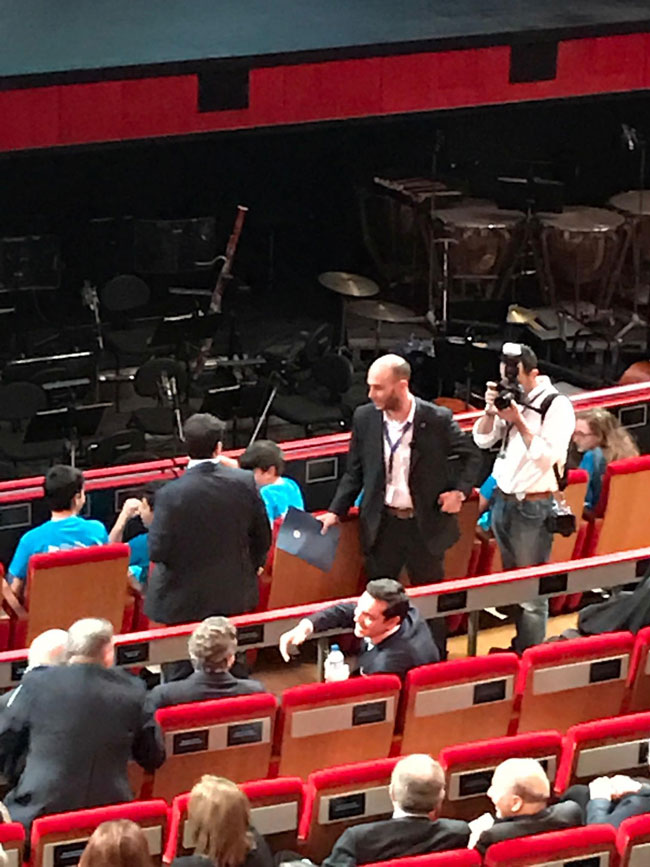  Προσέρχεται ο Αλέξης Τσίπρας, δεν αναγνωρίζει τον Φίλιππο Νιάρχο, τον προσπερνά και κάθεται μια θέση παραδίπλα. Στο τέλος αναλαμβάνει τις συστάσεις ο Νίκος Βούτσης.