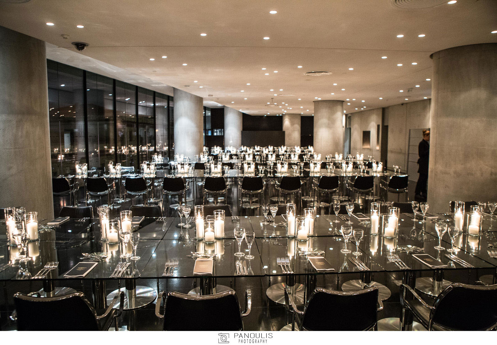 Ο στολισμός του εστιατορίου καλαίσθητος και μίνιμαλ με φόντο το φωτισμένο  βράχο minimal της Ακρόπολης.