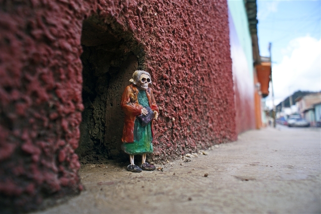 O Isaac Cordal, γεννημένος το 1974, είναι Ισπανός καλλιτέχνης από τη Γαλικία και ζει στις Βρυξέλλες. Τα έργα του συνδυάζουν τη μικρογλυπτική με τη φωτογραφία μέσα στο αστικό τοπίο. Έχει σπουδάσει γλυπτική, έχει ειδικευτεί στην τεχνική της πέτρας και υπήρξε μέλος καλλιτεχνικών ομάδων, γκρουπ της death metal μουσικής σκηνής της Ισπανίας καθώς και εκδότης του fanzine Exorcism. Αυτό που κάνει ο Ισπανός καλλιτέχνης είναι κάτι περισσότερο από urban art. Θα έλεγε κανείς ότι είναι ένα παιχνίδι «κρυμμένου θησαυρού», η δημιουργία ενός μικρόκοσμου μέσα στην πόλη και στις μυστικές γωνιές της. Δημιουργεί μικρές ανθρώπινες φιγούρες (περίπου 15 εκ. ύψος) από πηλό, κατασκευάζει καλούπια και μετά τις μετατρέπει σε φιγούρες από τσιμέντο, συνήθως ανθρώπους businessmen με καφκική διάθεση, που τους στήνει σε πόζες, μόνους ή όλους μαζί στο σύμπαν της πόλης, σατιρίζοντας σκληρά τον σύγχρονο κόσμο, την κλιματική αλλαγή, τη γραφειοκρατία, τη μοναξιά. Συνήθως είναι δύσκολο να τα ανακαλύψεις με την πρώτη ματιά, πρέπει να ψάξεις ιδιαίτ O Isaac Cordal, γεννημένος το 1974, είναι Ισπανός καλλιτέχνης από τη Γαλικία και ζει στις Βρυξέλλες. Τα έργα του συνδυάζουν τη μικρογλυπτική με τη φωτογραφία μέσα στο αστικό τοπίο. Έχει σπουδάσει γλυπτική, έχει ειδικευτεί στην τεχνική της πέτρας και υπήρξε μέλος καλλιτεχνικών ομάδων, γκρουπ της death metal μουσικής σκηνής της Ισπανίας καθώς και εκδότης του fanzine Exorcism. Αυτό που κάνει ο Ισπανός καλλιτέχνης είναι κάτι περισσότερο από urban art. Θα έλεγε κανείς ότι είναι ένα παιχνίδι «κρυμμένου θησαυρού»