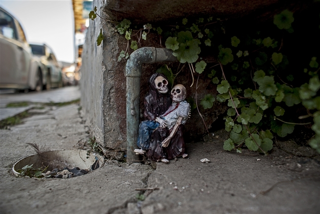 O Isaac Cordal, γεννημένος το 1974, είναι Ισπανός καλλιτέχνης από τη Γαλικία και ζει στις Βρυξέλλες. Τα έργα του συνδυάζουν τη μικρογλυπτική με τη φωτογραφία μέσα στο αστικό τοπίο. Έχει σπουδάσει γλυπτική, έχει ειδικευτεί στην τεχνική της πέτρας και υπήρξε μέλος καλλιτεχνικών ομάδων, γκρουπ της death metal μουσικής σκηνής της Ισπανίας καθώς και εκδότης του fanzine Exorcism. Αυτό που κάνει ο Ισπανός καλλιτέχνης είναι κάτι περισσότερο από urban art. Θα έλεγε κανείς ότι είναι ένα παιχνίδι «κρυμμένου θησαυρού», η δημιουργία ενός μικρόκοσμου μέσα στην πόλη και στις μυστικές γωνιές της. Δημιουργεί μικρές ανθρώπινες φιγούρες (περίπου 15 εκ. ύψος) από πηλό, κατασκευάζει καλούπια και μετά τις μετατρέπει σε φιγούρες από τσιμέντο, συνήθως ανθρώπους businessmen με καφκική διάθεση, που τους στήνει σε πόζες, μόνους ή όλους μαζί στο σύμπαν της πόλης, σατιρίζοντας σκληρά τον σύγχρονο κόσμο, την κλιματική αλλαγή, τη γραφειοκρατία, τη μοναξιά. Συνήθως είναι δύσκολο να τα ανακαλύψεις με την πρώτη ματιά, πρέπει να ψάξεις ιδιαίτ O Isaac Cordal, γεννημένος το 1974, είναι Ισπανός καλλιτέχνης από τη Γαλικία και ζει στις Βρυξέλλες. Τα έργα του συνδυάζουν τη μικρογλυπτική με τη φωτογραφία μέσα στο αστικό τοπίο. Έχει σπουδάσει γλυπτική, έχει ειδικευτεί στην τεχνική της πέτρας και υπήρξε μέλος καλλιτεχνικών ομάδων, γκρουπ της death metal μουσικής σκηνής της Ισπανίας καθώς και εκδότης του fanzine Exorcism. Αυτό που κάνει ο Ισπανός καλλιτέχνης είναι κάτι περισσότερο από urban art. Θα έλεγε κανείς ότι είναι ένα παιχνίδι «κρυμμένου θησαυρού»