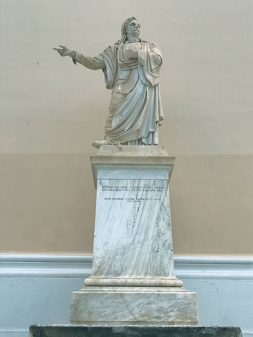 Το άγαλμα του Ρήγα Φεραίου μπροστά από την Τριλογία