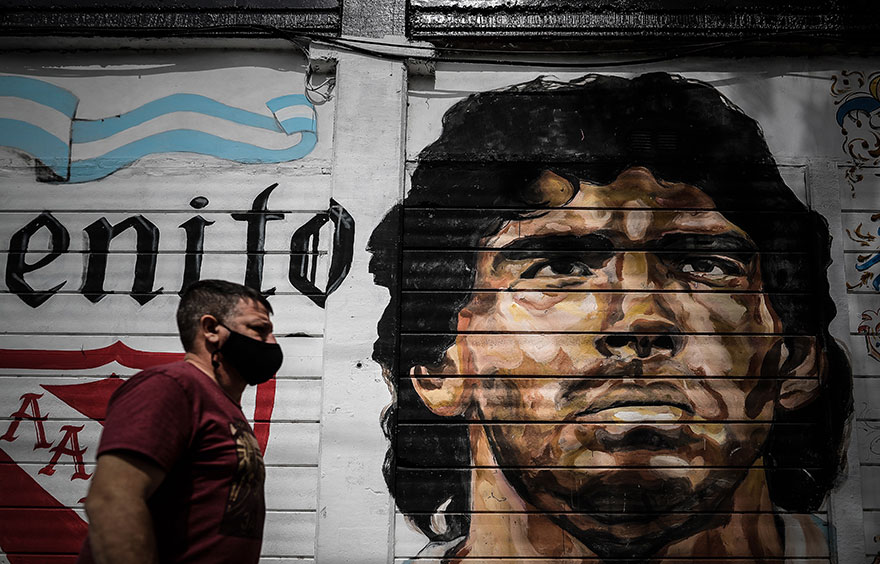 Άνδρας με προστατευτική μάσκα για τον κορωνοϊό περνά μπροστά από mural του Μαραντόνα στο Μπουένος Άιρες