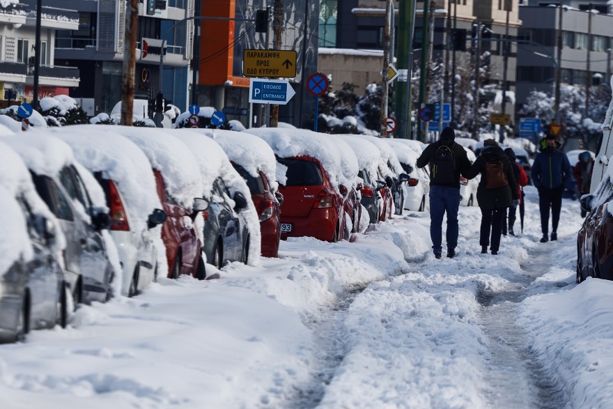 Κακοκαιρία «Ελπίδα»: Πολίτες περπατούν πάνω στη Μεσογείων λόγω του χιονιού που βρίσκεται στα πεζοδρόμια
