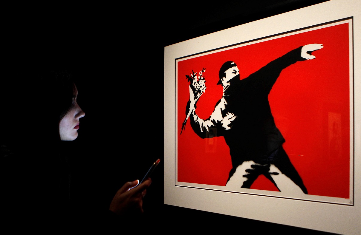 Γυναίκα που κοιτά το smartphone της σε έκθεση με έργα του Banksy