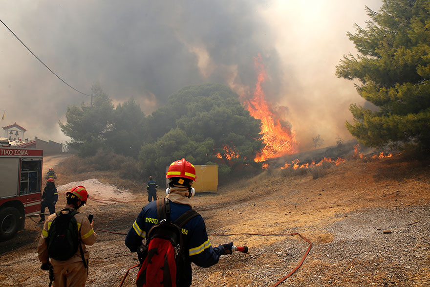 Πυροσβέστες με τη μάνικα στο χέρι έτοιμοι να ανακόψουν τη φωτιά που πλησιάζει σπίτια