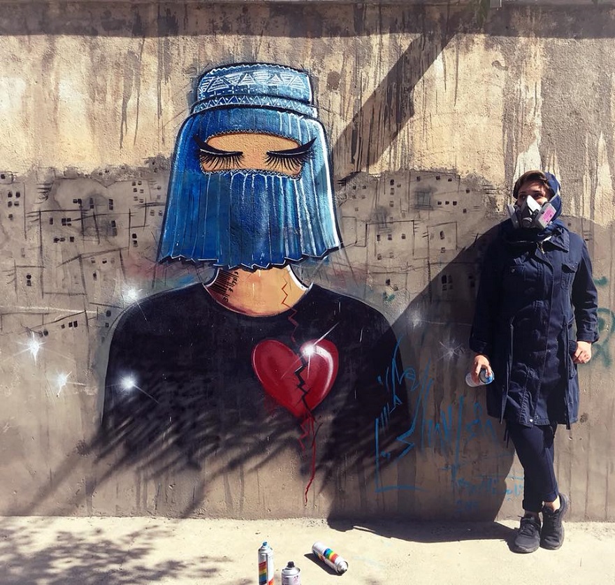 Η Σάμσια Χασάνι δίπλα από έργο της σε τοίχο του Αφγανιστάν.